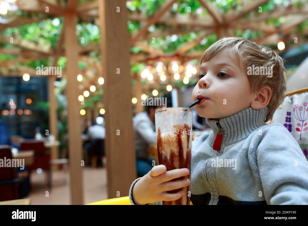 Enfant buvant un milk shake à table dans le restaurant Banque D'Images