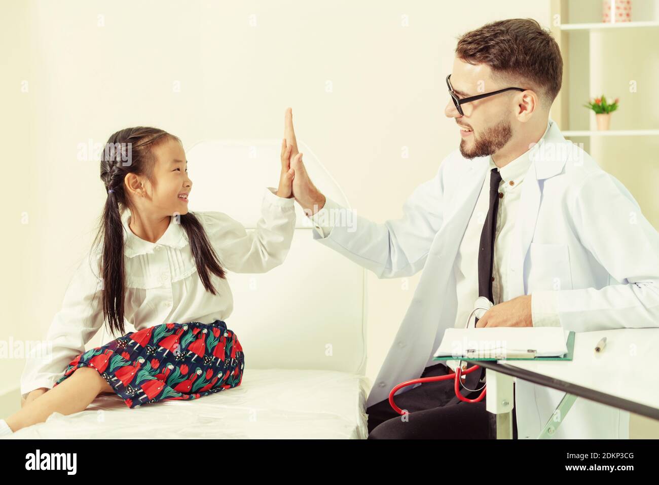 Jeune homme médecin examinant petit enfant à l'hôpital. L'enfant est heureux et pas peur du médecin. Soins médicaux les enfants concept. Banque D'Images