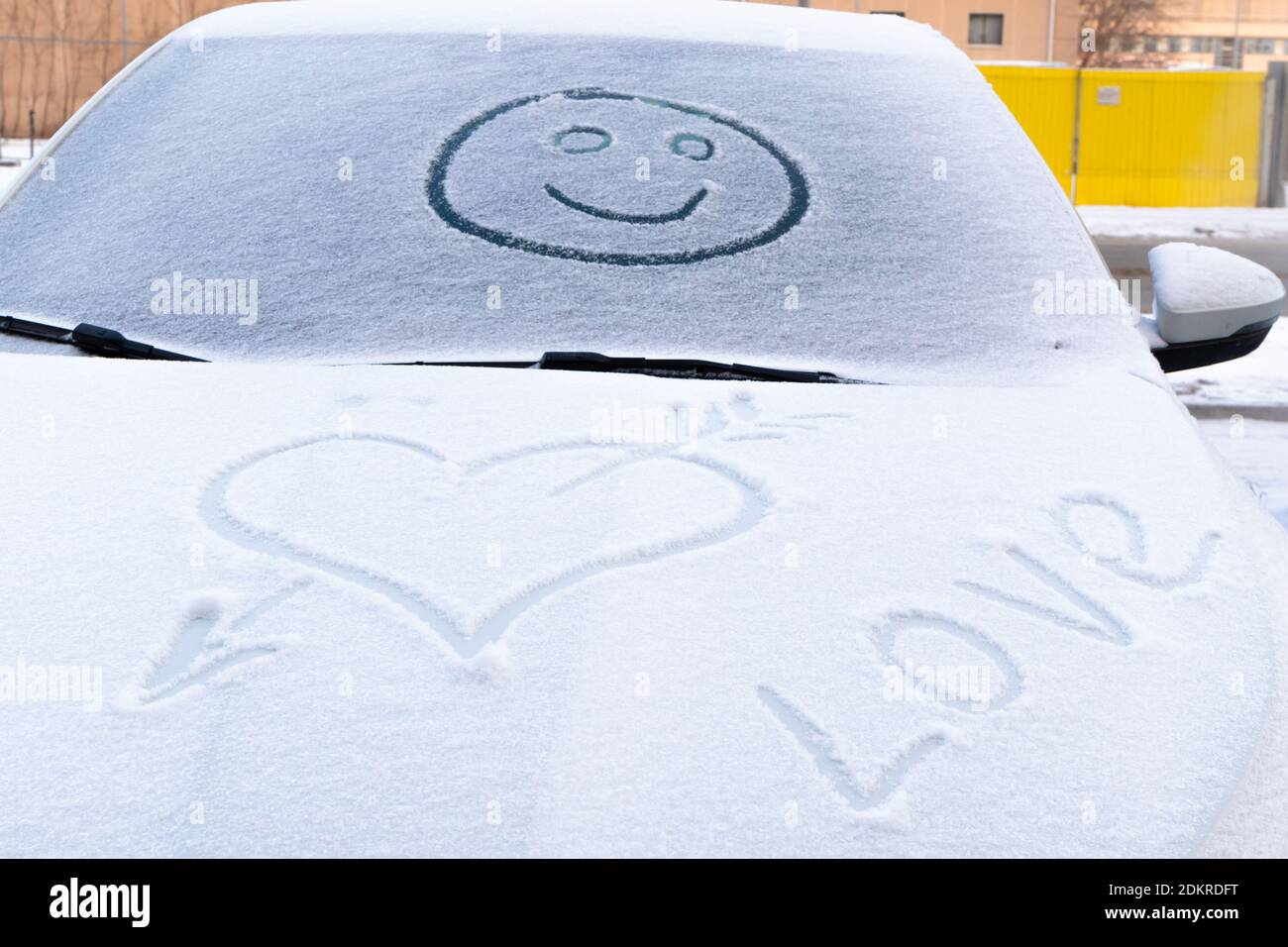 image d'un visage souriant dans la neige sur le pare-brise d'une voiture et forme de coeur sur un hiver glacial Banque D'Images