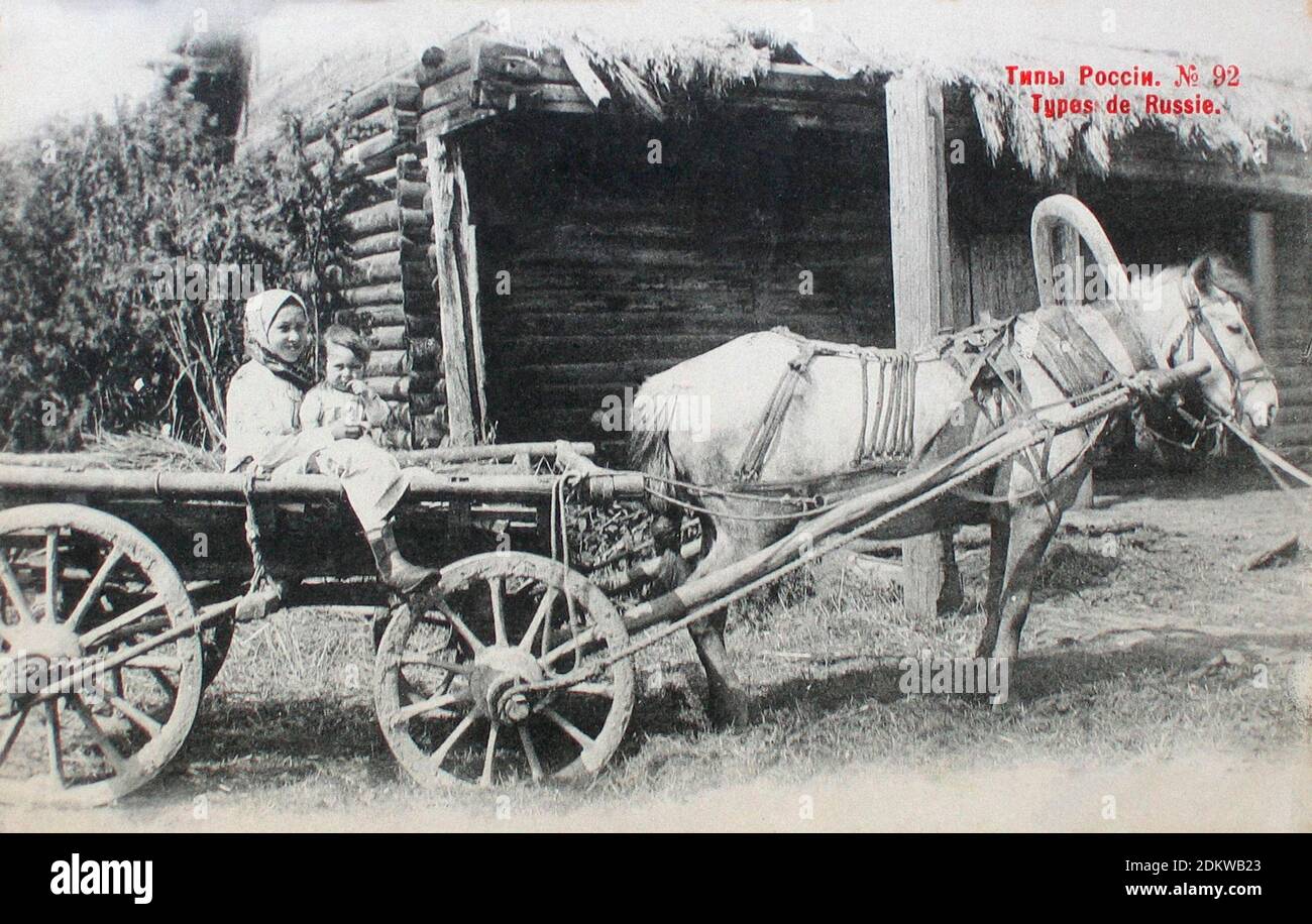 Carte postale rétro de types et costumes de Russie. Une jeune paysanne avec un enfant dans un chariot. Empire russe. 1904 Banque D'Images