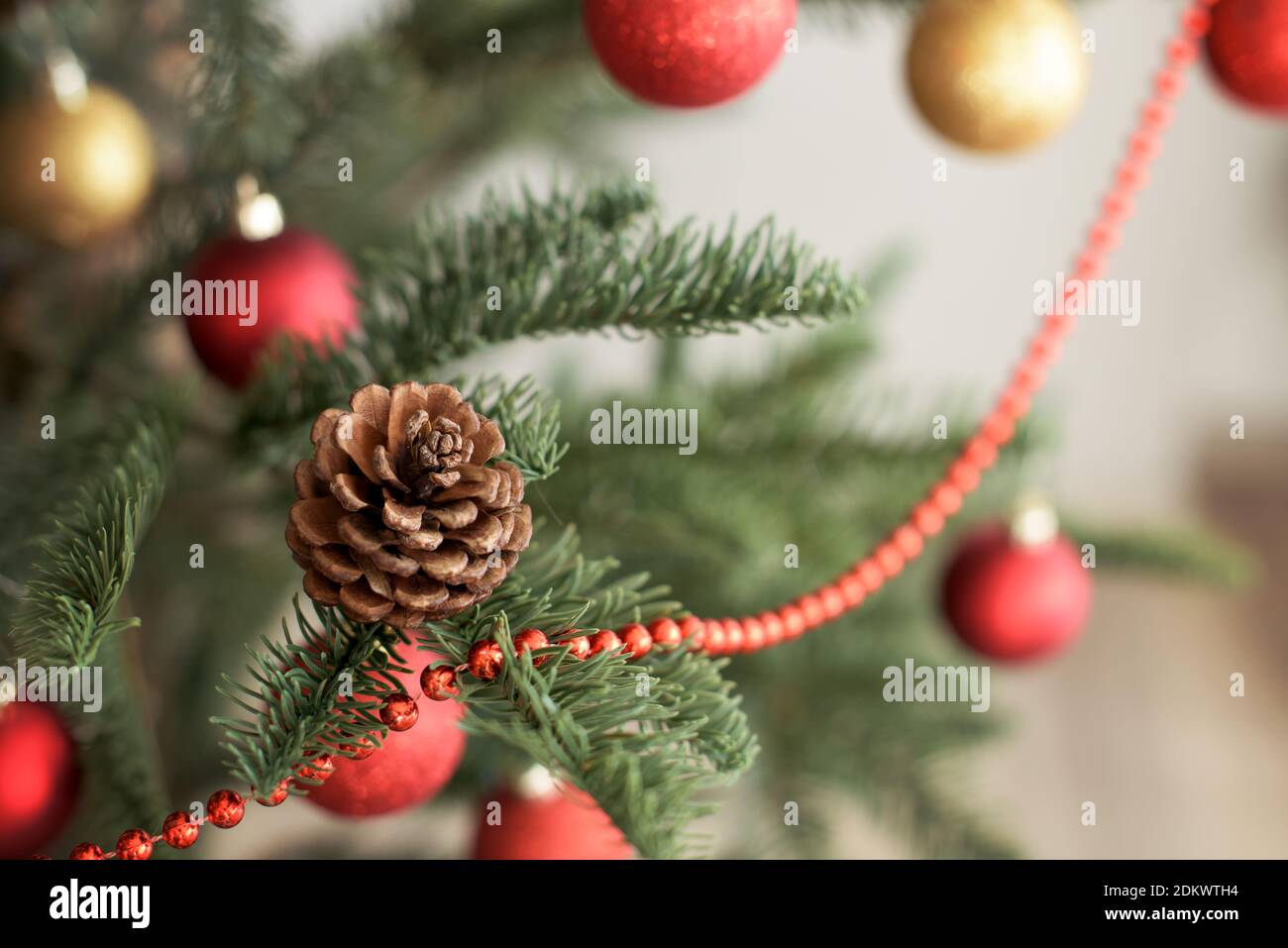 Cône de sapin sur un arbre de Noël doré et rouge décoré Banque D'Images