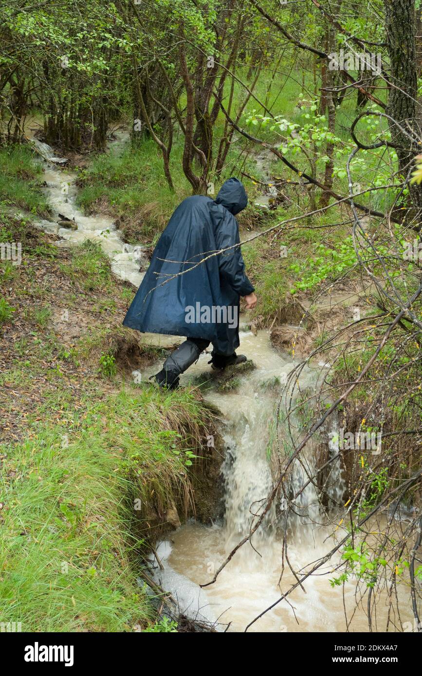 Pèlerin traversant un ruisseau lors d'un jour de pluie lors de son pèlerinage le long du Camino de Santiago. Banque D'Images