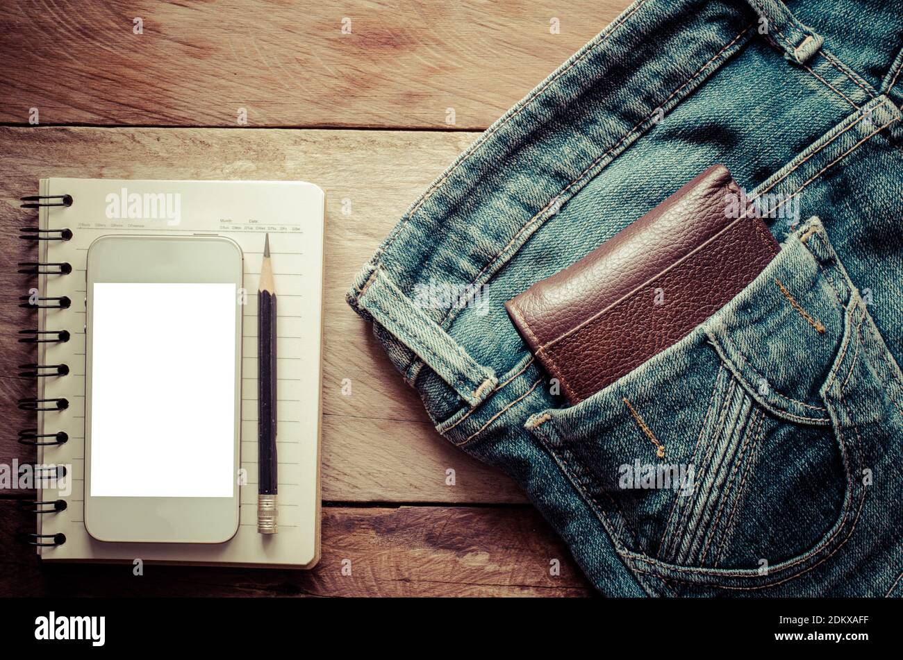 Portefeuille par téléphone portable et Livre en Jean poche sur la table Banque D'Images