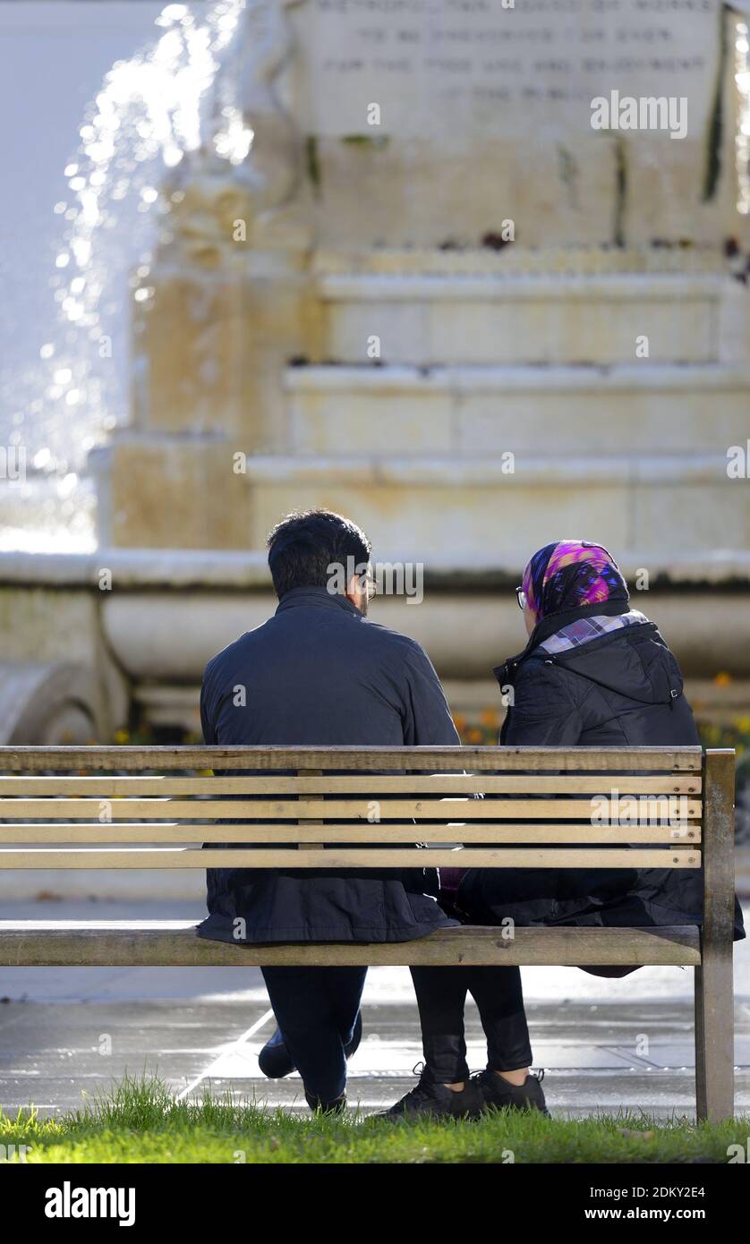 Londres, Angleterre, Royaume-Uni. Couple asiatique assis sur un banc à Leicester Square Banque D'Images