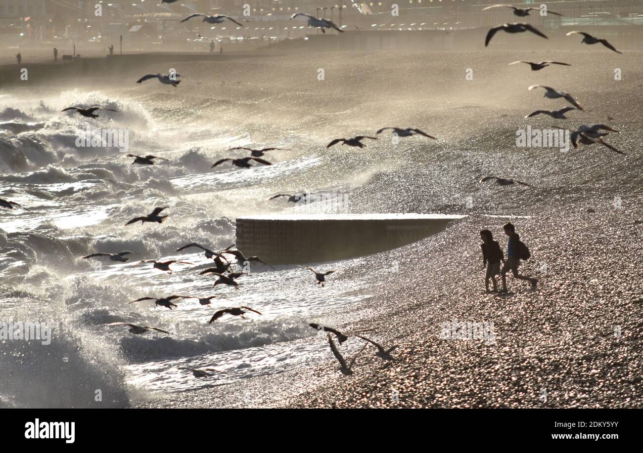 Silhouettes de deux enfants qui s'exécutent sur une plage avec des vagues Banque D'Images