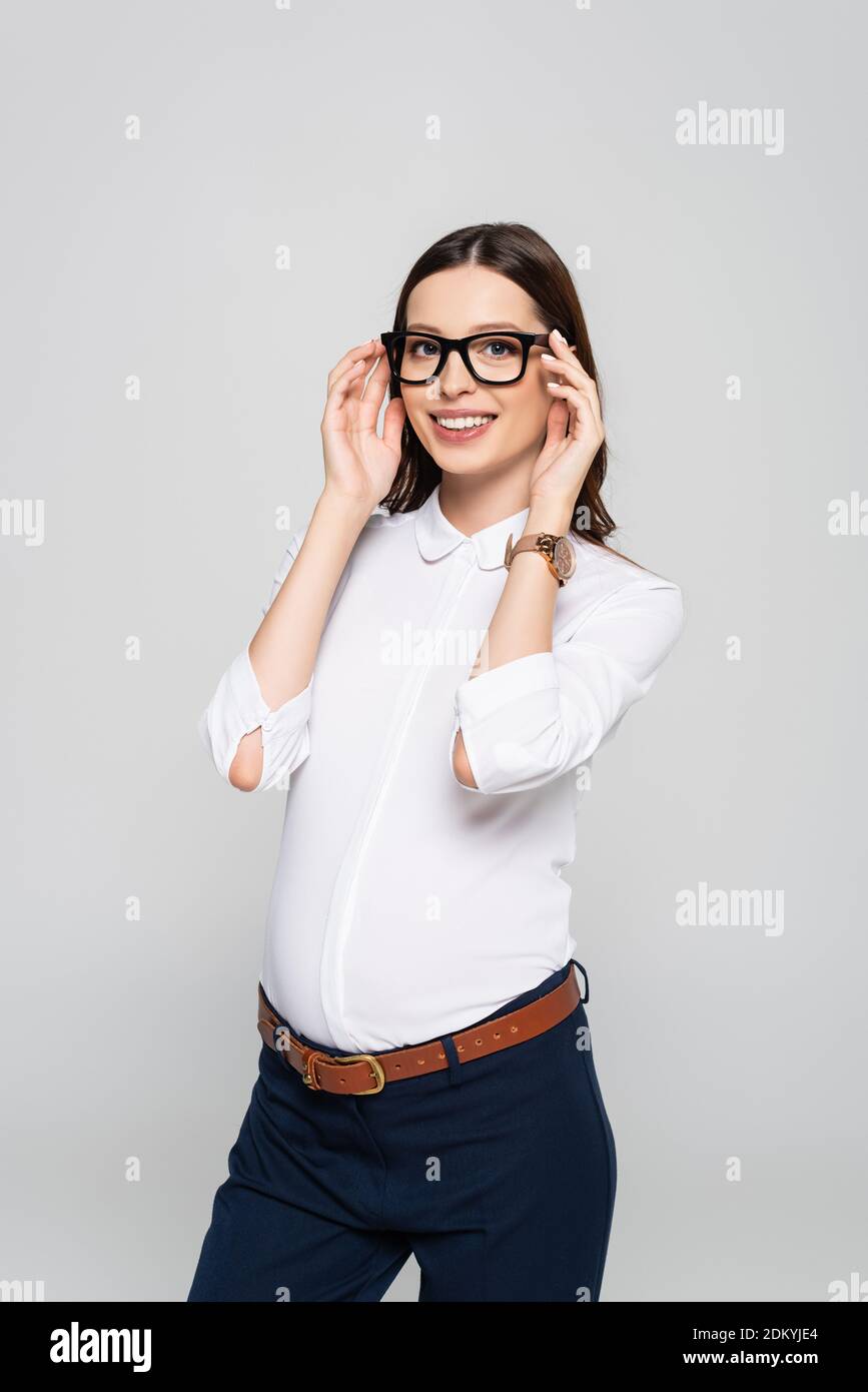 jeune femme d'affaires souriante enceinte dans des lunettes isolées sur le gris Banque D'Images