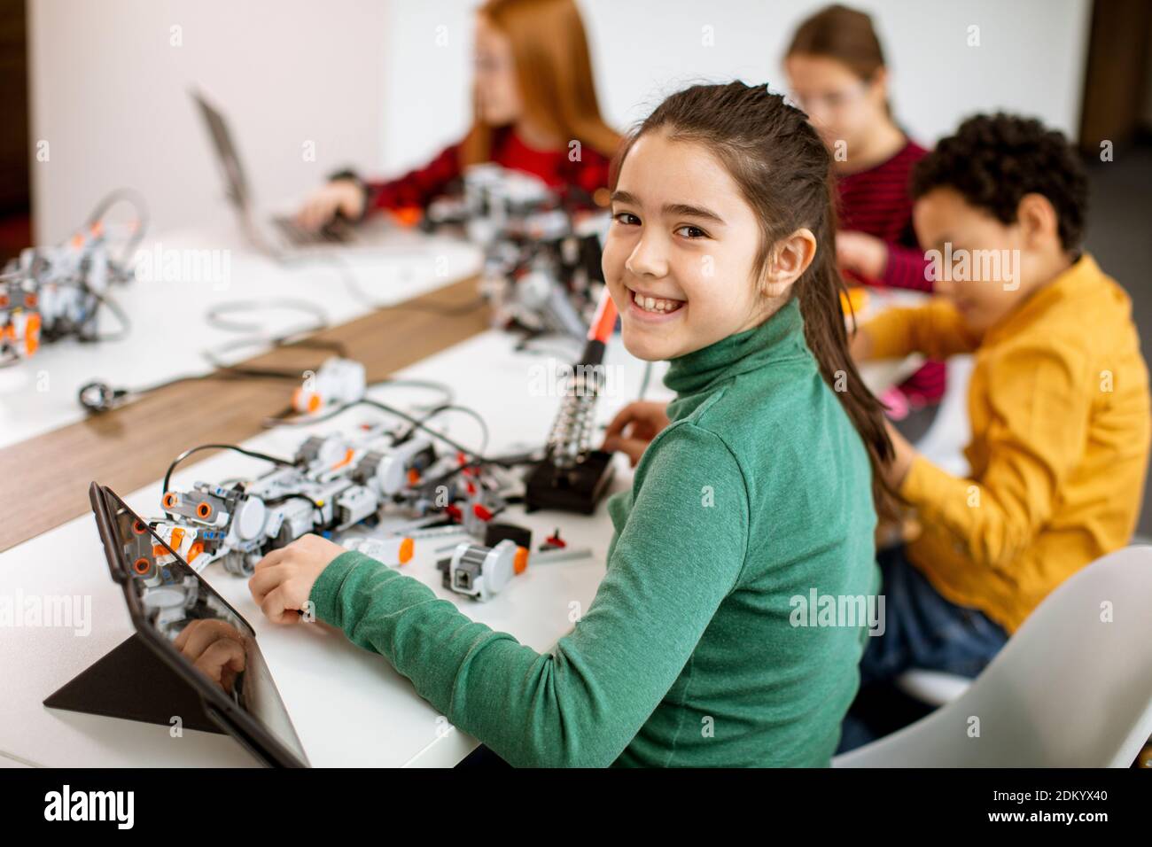 Groupe d'enfants heureux programmant des jouets électriques et des robots à salle de classe robotique Banque D'Images