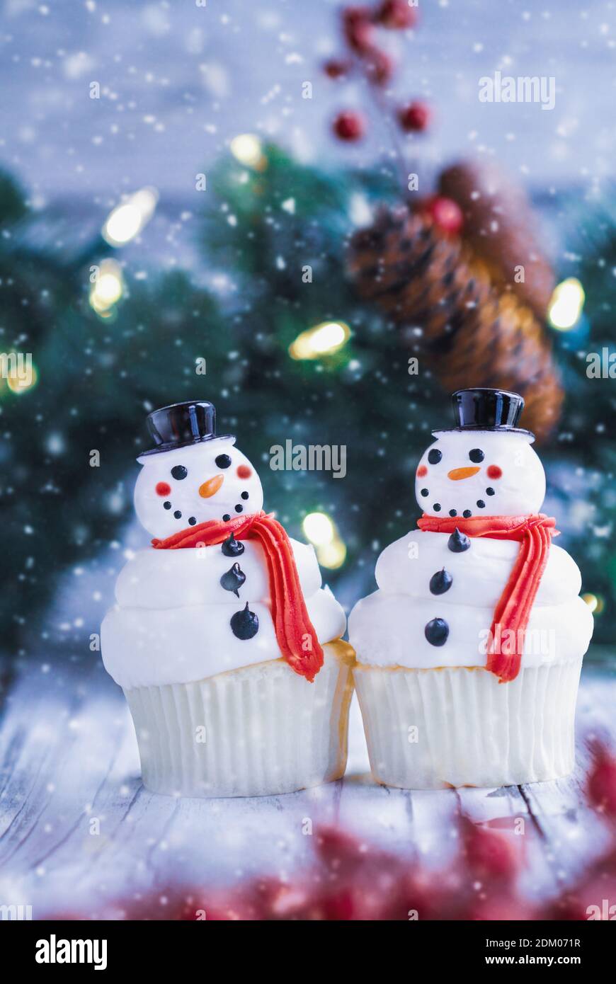 Deux cupcakes de Noël glacés avec nez de carotte, chapeau de père noël et foulard. Mise au point sélective avec un premier plan et un arrière-plan flous. Banque D'Images