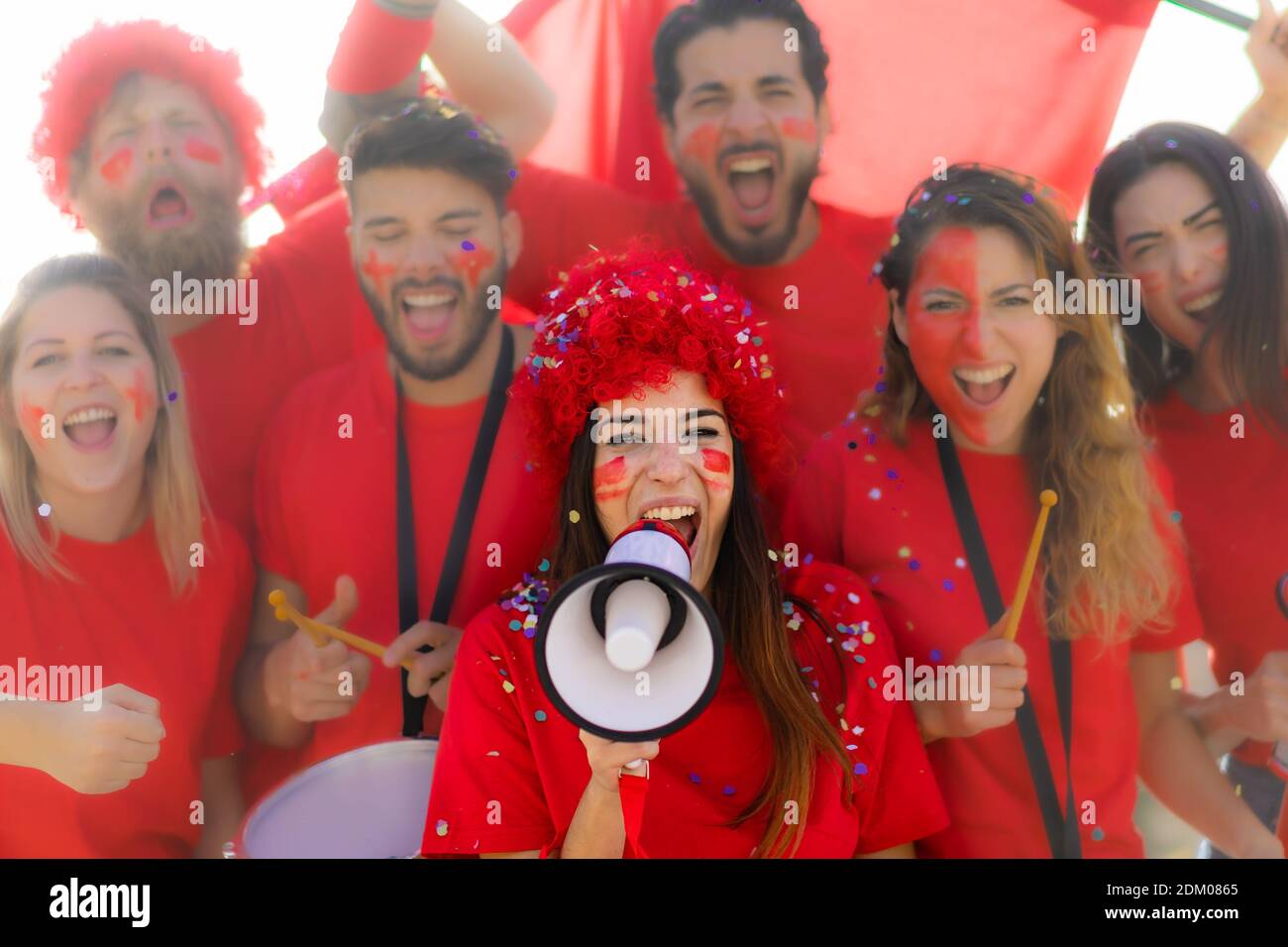 Un fan de football hurle, avec des chemises rouges dans le stade. Groupe de jeunes très enthousiastes au sujet du sport. Concept sport et fun. Concentrez-vous sur le visage des filles avec Banque D'Images