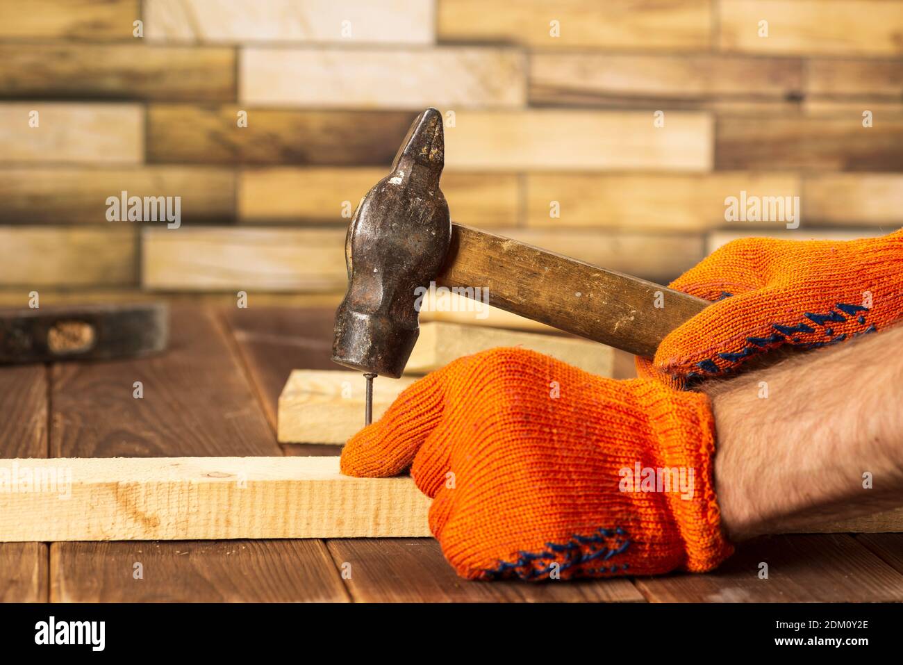 Gros plan d'un menuisier en gants de travail orange, qui fait un clou dans  un panneau en bois Photo Stock - Alamy