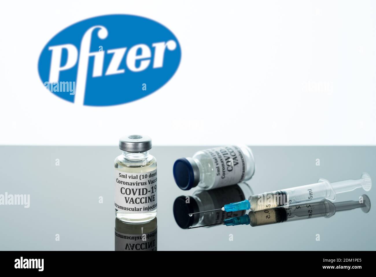 Morgantown, WV - 16 décembre 2020 : petite bouteille de vaccin contre le coronavirus avec seringue avec fond du logo Pfizer Banque D'Images