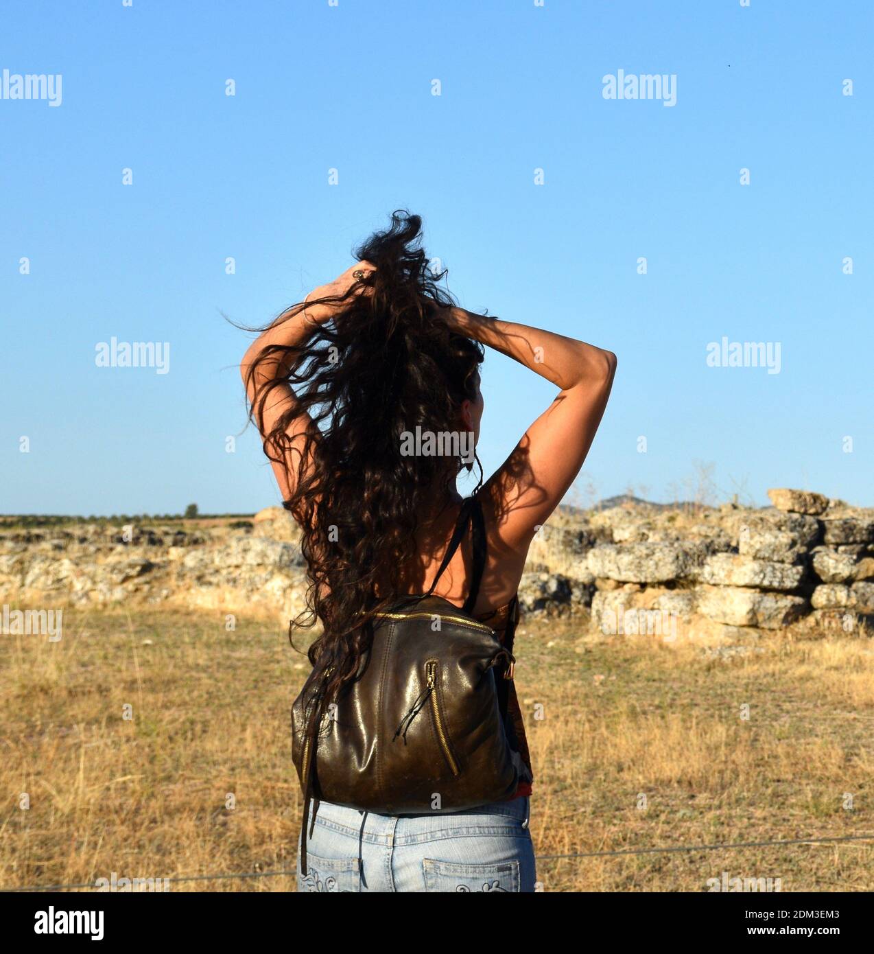 Latina fille de derrière lui attrapant ses longs cheveux de brunette. Banque D'Images