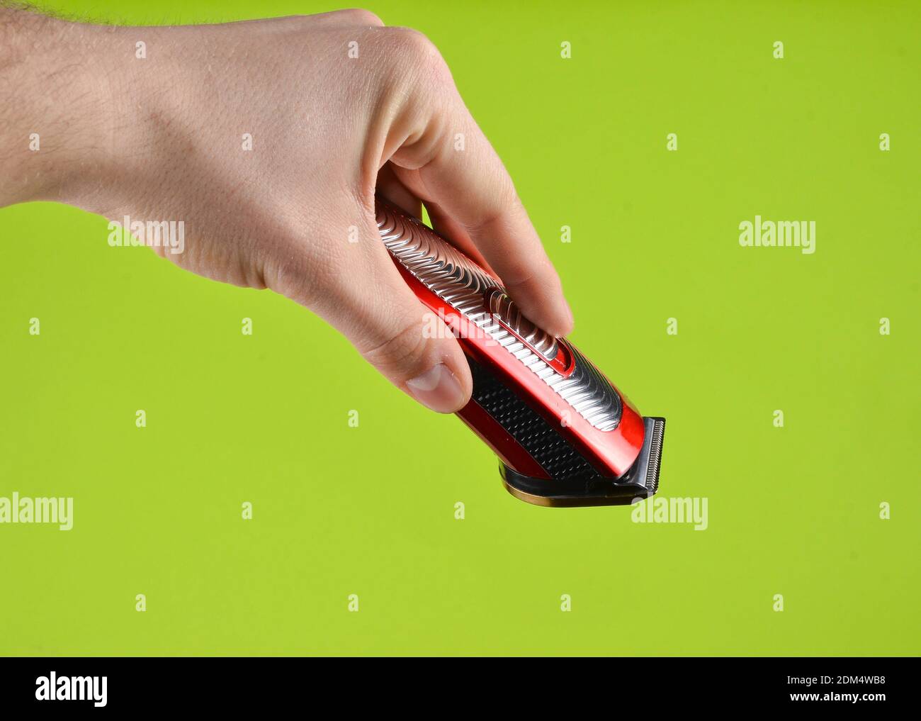 Tondeuse sans fil dans une main mâle isolée sur un green arrière-plan Banque D'Images