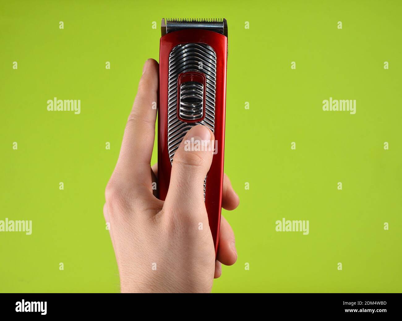 Tondeuse sans fil dans une main mâle isolée sur un green arrière-plan Banque D'Images