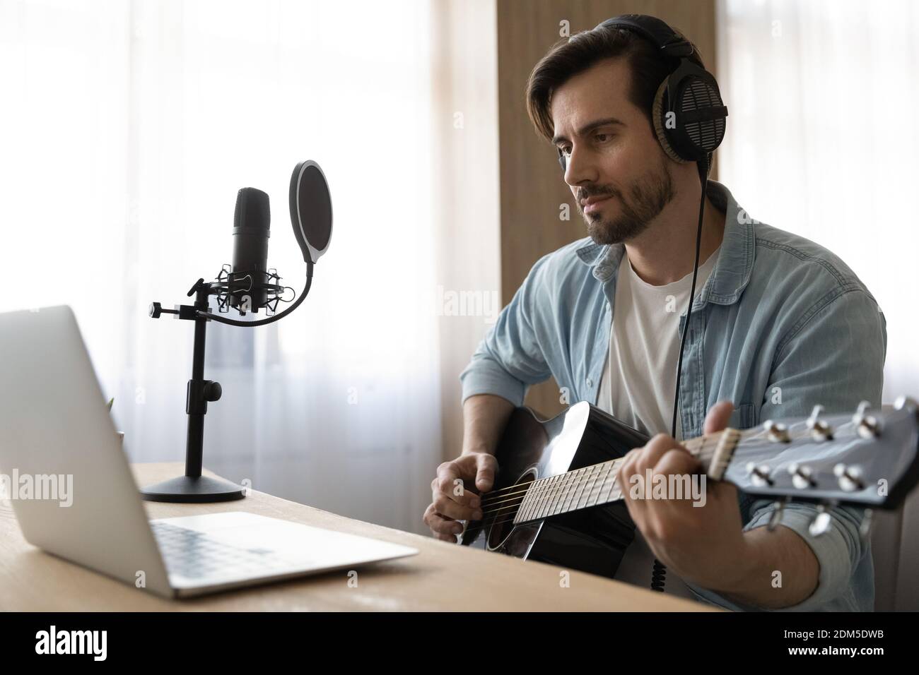 Un jeune artiste masculin apprend à jouer de la guitare en ligne Banque D'Images