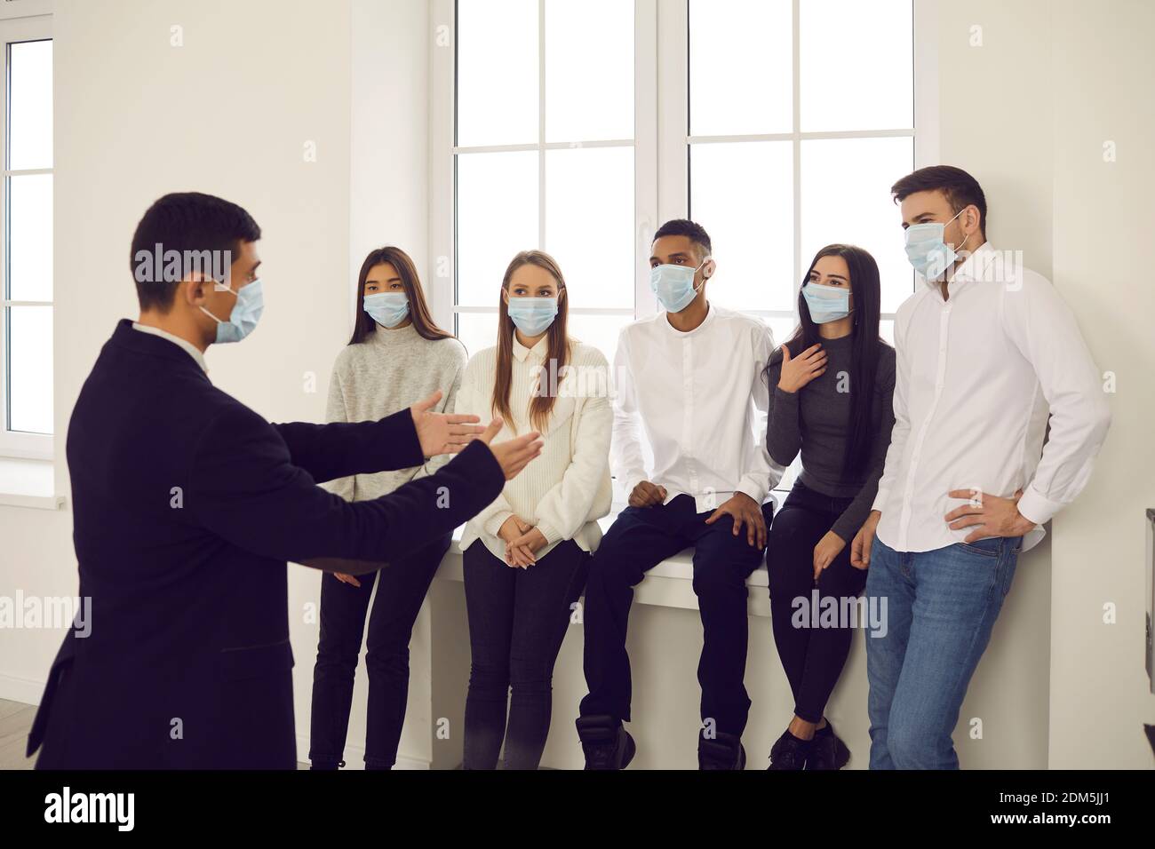 Un coach d'affaires ou un responsable d'équipe de l'entreprise qui parle aux jeunes tous portent des masques Banque D'Images