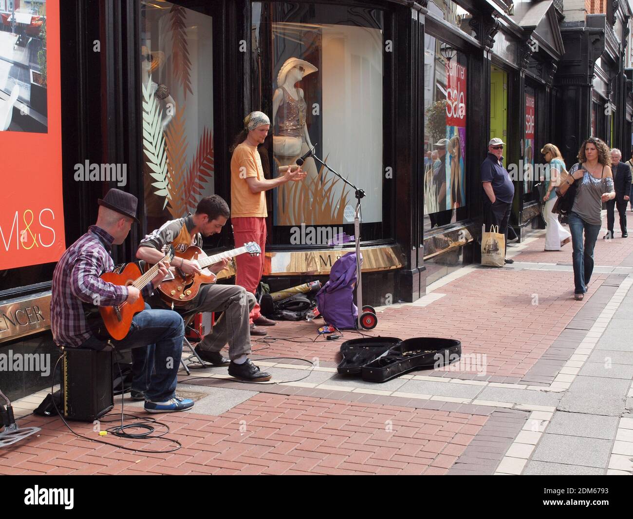 Dublin Irlande musiciens de rue se produisent pour les locaux et les touristes pour gagner des conseils. Les passants regardent la promenade. Banque D'Images