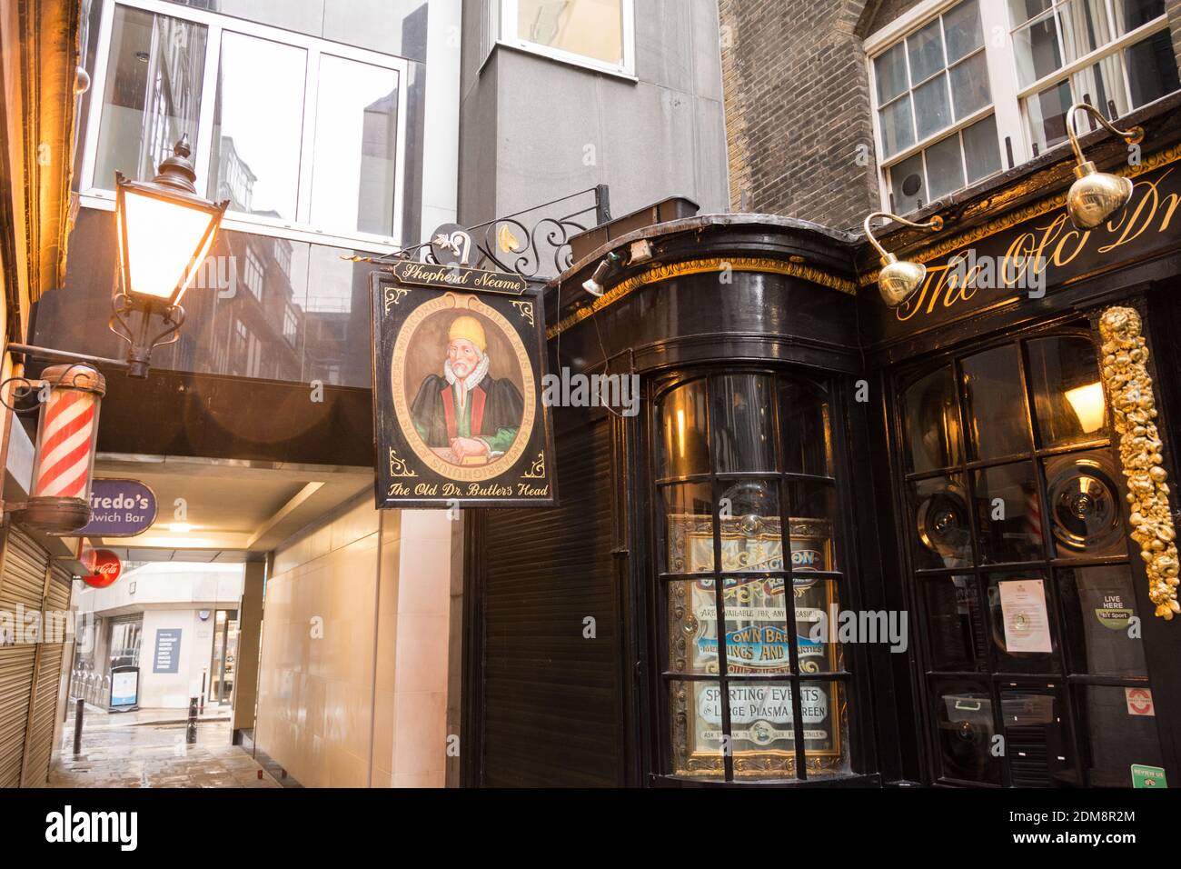 Un poteau de barbier et une affiche de pub à l'extérieur du pub Old Doctor Butler's Head sur Masons Ave, Londres, EC2, City of London, Royaume-Uni Banque D'Images