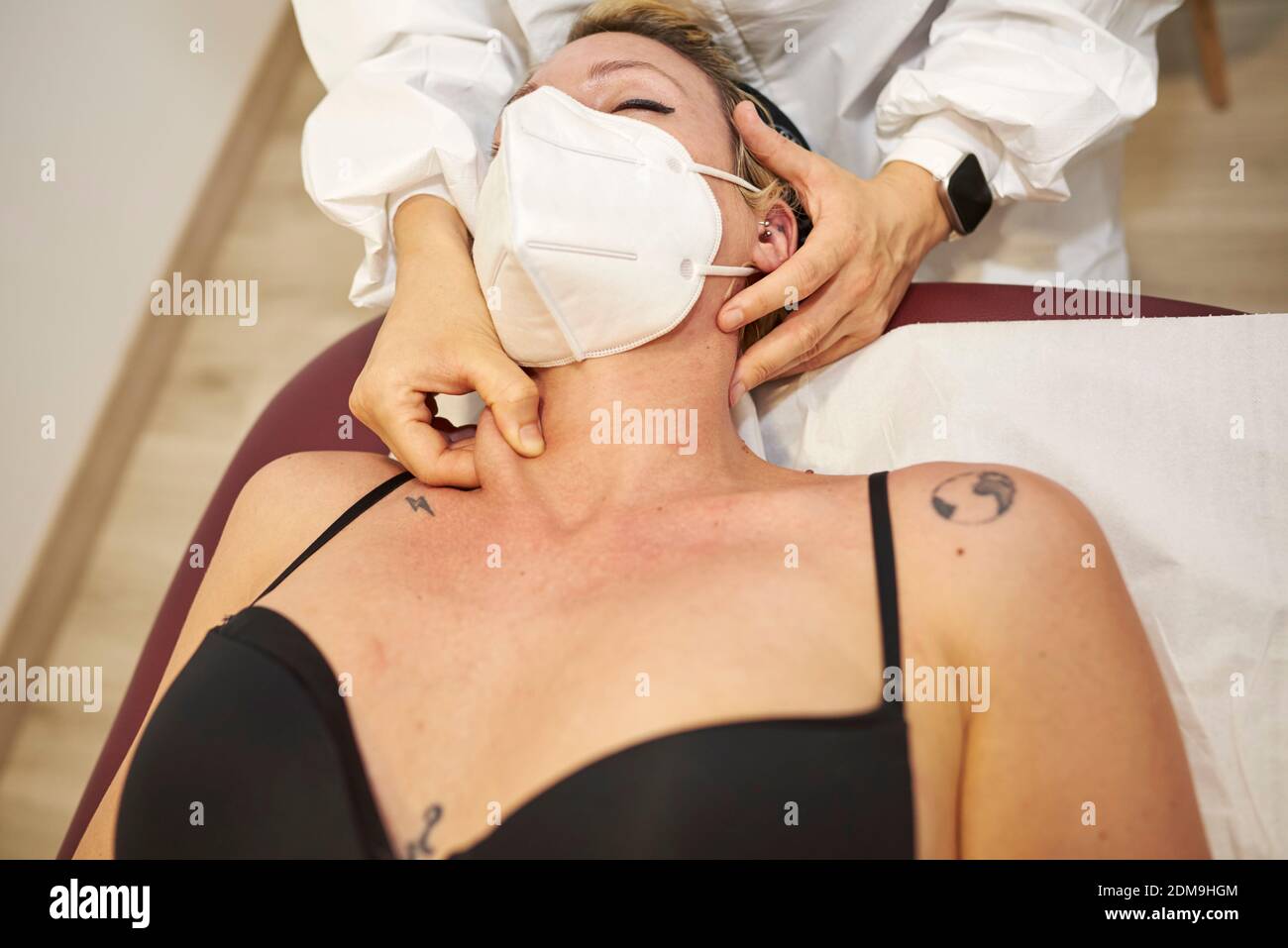 Un physiothérapeute médical donne un massage du cou à son patient. Ils ont des masques de sécurité pour empêcher la propagation de Covid-19. Banque D'Images