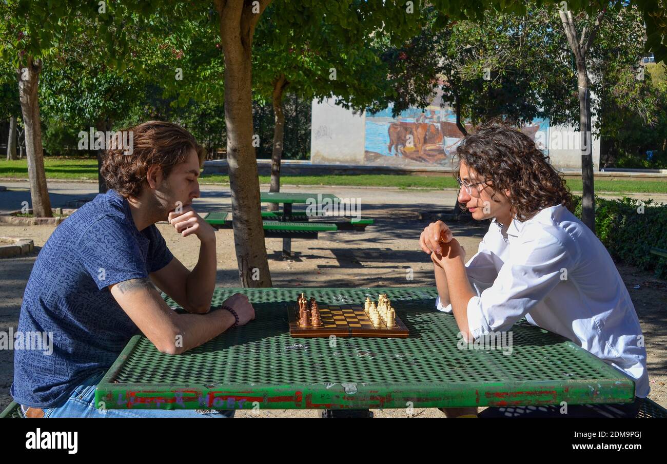 Un gros plan de deux gars jouant aux échecs dans le garez-vous près des arbres sur le banc Banque D'Images