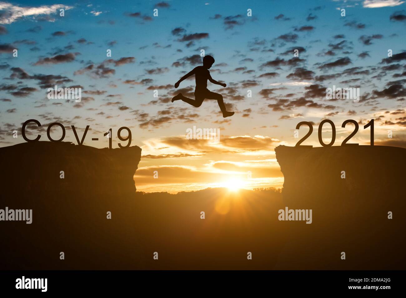Concept de la nouvelle année 2021. Silhouette d'homme saut sur la falaise entre 2020 (Covid-19) à 2021 ans sur fond de coucher ou de lever de soleil. Banque D'Images