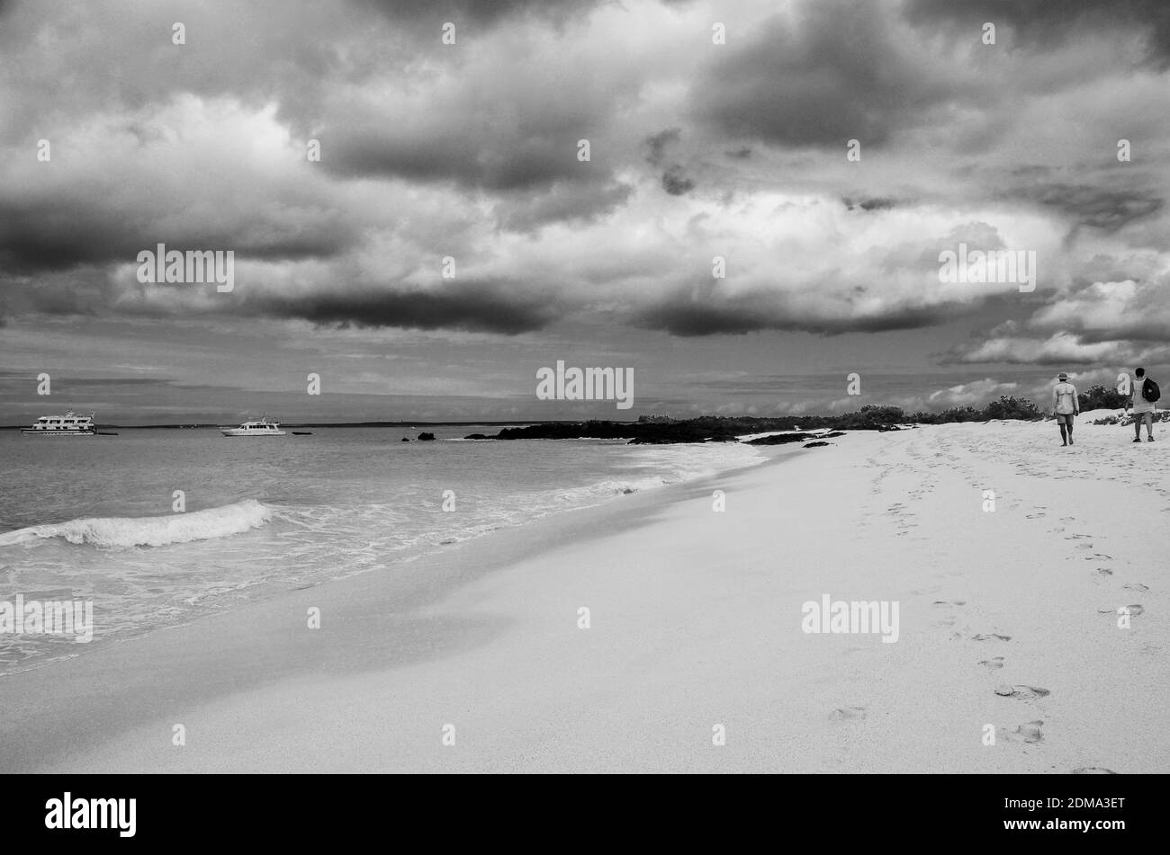Deux personnes marchant le long de la plage de sable sur une île déserte de Galapagos Banque D'Images