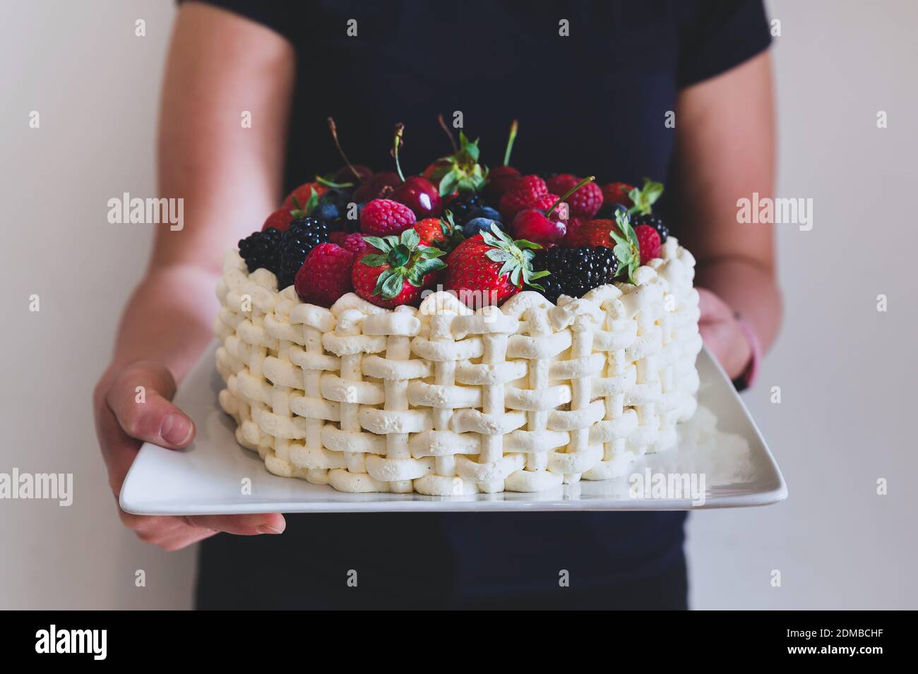 Femme Tenant Une Assiette Avec Beau Gateau D Ete Decore De Baies Sur Fond De Mur Blanc Photo Stock Alamy