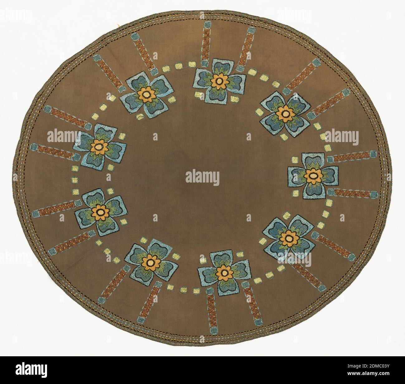 Table ronde, moyenne: Coton, acétate technique: Brodée sur un tissage simple, table ronde grise avec une bordure intérieure de carrés jaune-vert entourée en bleu avec rayons rayonnants brodés en marron, or et bleu clair. À l'intérieur de la bordure intérieure se trouvent des croix bleu clair, soulignées en noir, qui contiennent des formes florales lobées en bleu foncé avec des centres jaune et vert. Fabriqué à partir d'un kit de broderie. Voir 5896.42.2019., États-Unis, ca. 1910, broderie et couture, Table ronde Banque D'Images