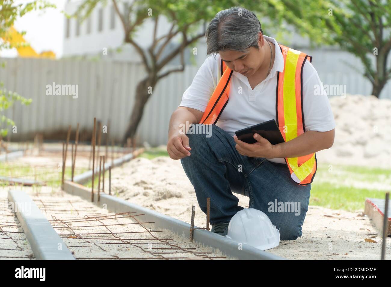 L'ingénierie, portant un casque et holding tablets, s'assoir pour vérifier la structure du couloir dans le parc Banque D'Images