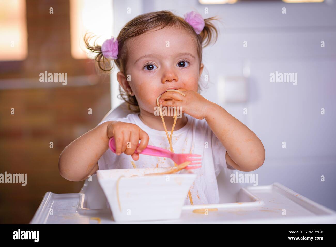 Mignon Petite Fille Drole De 18 Mois 1 An Bebe Fille Assis Dans Une Chaise Haute Puissance A La Maison Mange Des Nouilles Avec Cuillere Et Fourchette Photo A L Interieur De Mignon Petite Fille Drole De 18 Mois 1 An Bebe Fille Assis Dans Une Chaise Haute Puissance A La Maison Mange Des Nouilles Avec Cuillere Et Fourchette Photo A L Interieur De