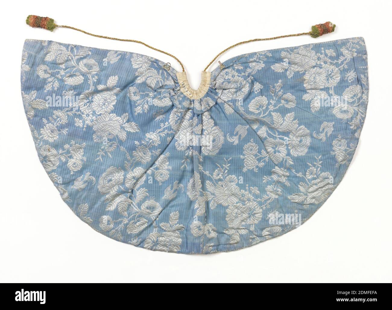 Cape pour une figurine ecclésiastique, milieu: Soie, fils métalliques, paillettes technique: Brodée sur la doire, petite cape pour une figure ecclésiastique, le 'Bambino'. Robe de soie blanche brodée avec chenille de soie dans les verts, les violets, rose, et paillettes d'or et fil d'or et d'argent. Conception de la bordure de vigne, de rose et de grain aroudn. Bordé de soie bleue et de fleurs brocardées blanches, France, 1750–99, costume et accessoires, cape pour une figurine ecclésiastique Banque D'Images