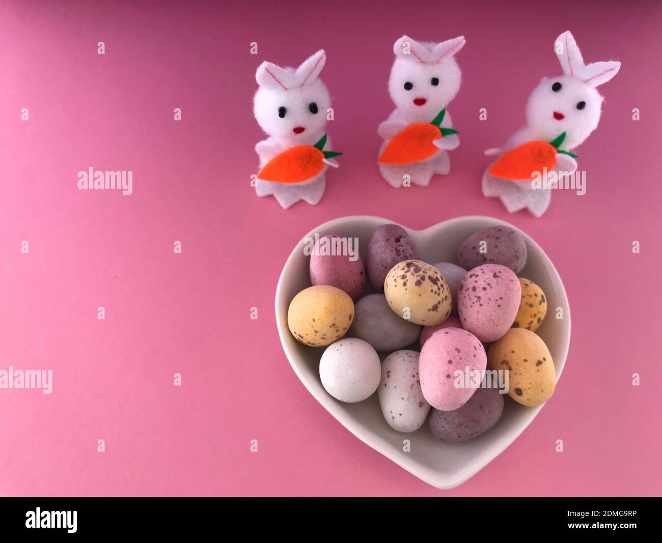 Mini-œufs de Pâques au chocolat enrobés de sucre dans un plat en forme de  coeur , et trois lapins de Pâques à jouets Photo Stock - Alamy