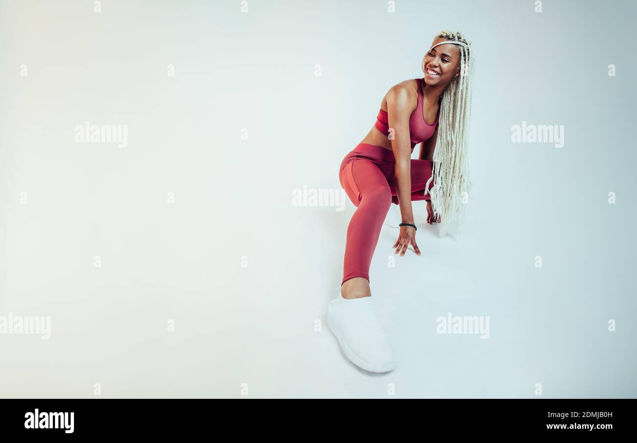 Femme de fitness afro-américaine s'entraîner sur fond blanc. Les femmes sportives s'étirent et s'échauffent avant de s'entraîner. Banque D'Images