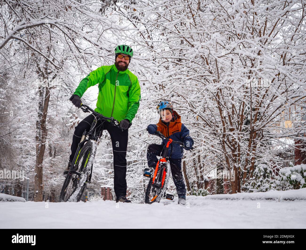 Père et fils avec vélos dans un parc d'hiver. Le père explique comment faire du vélo. Week-end dans le parc d'hiver Banque D'Images