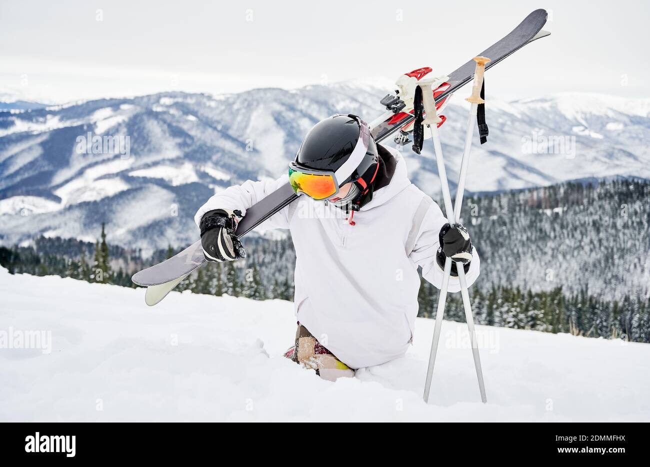 Skieur alpin en veste de snowboard tenant des skis et des bâtons de ski  tout en essayant de marcher dans la neige blanche profonde. Homme passant  des vacances en montagne. Concept Photo