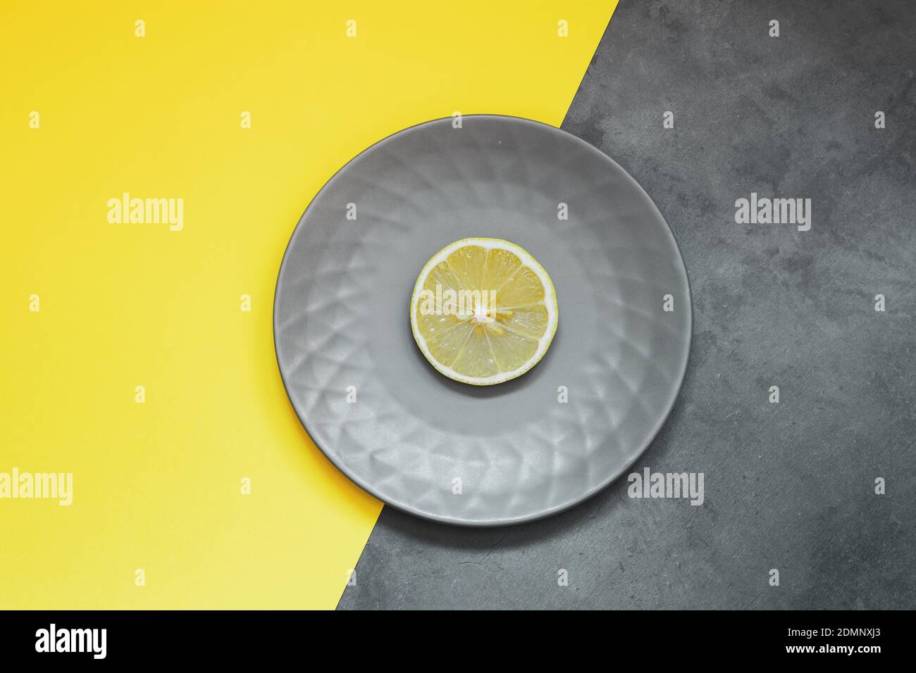 Assiette grise avec citron sur fond jaune. Couleurs tendance 2021 - gris  ultime et illuminant Photo Stock - Alamy