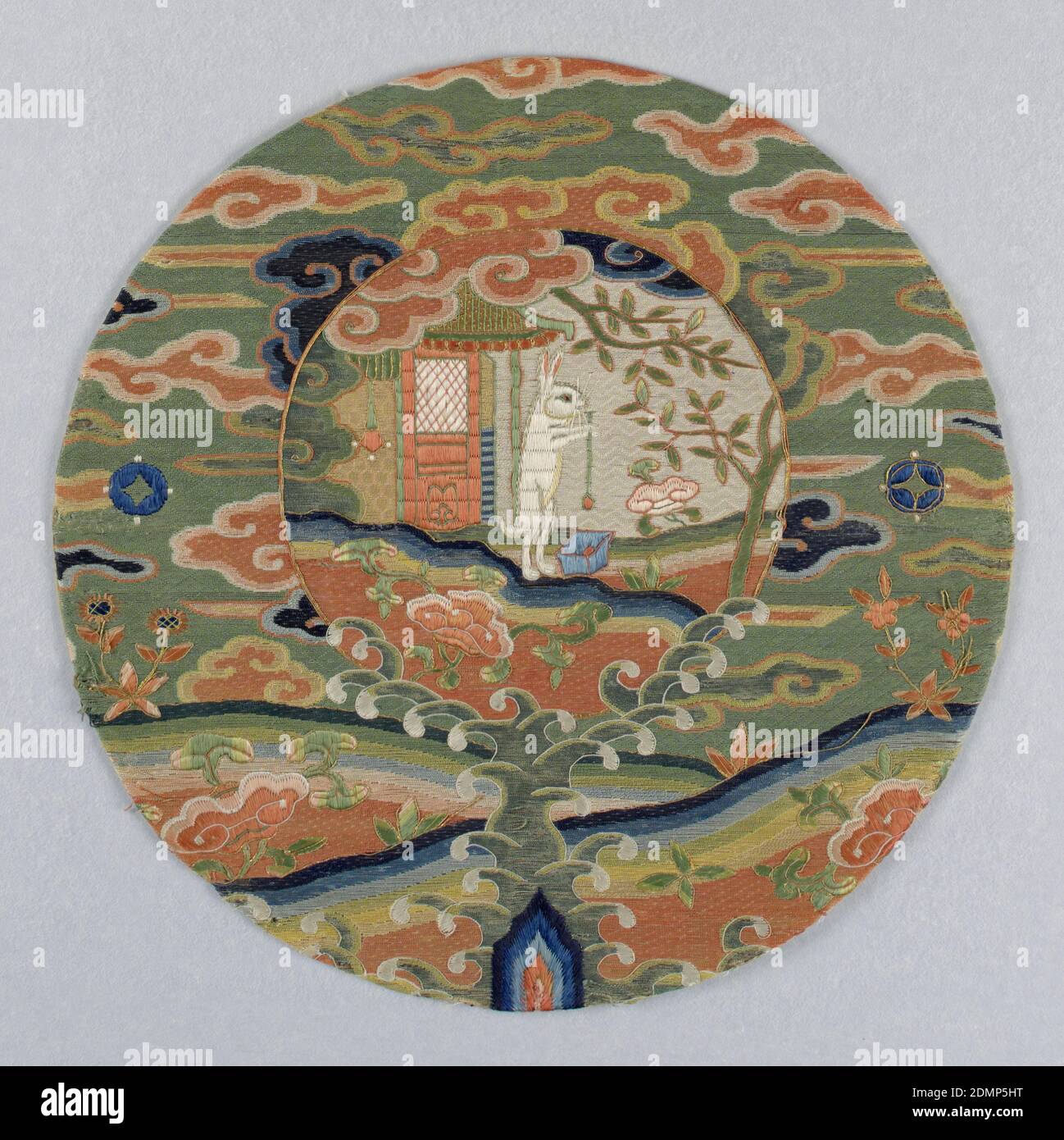 Lapin dans la Lune, Moyen: Soie, fils métalliques technique: Brodé en motif de dard, satin et coutures couching sur la base de gaze-tissage, médaillon circulaire avec un cadre et un centre pictural. Le cadre contient un paysage avec des motifs nuages brodés en soie polychrome sur un sol vert. Au centre, un lapin blanc est debout devant un petit bâtiment avec des arbres, remuant un vaisseau bleu avec une longue cuillère. Le lapin battant l'élixir de la vie est souvent montré sur la robe d'un prêtre T'aoïste., Chine, XVIIe siècle, broderie et couture, médaillon, médaillon Banque D'Images