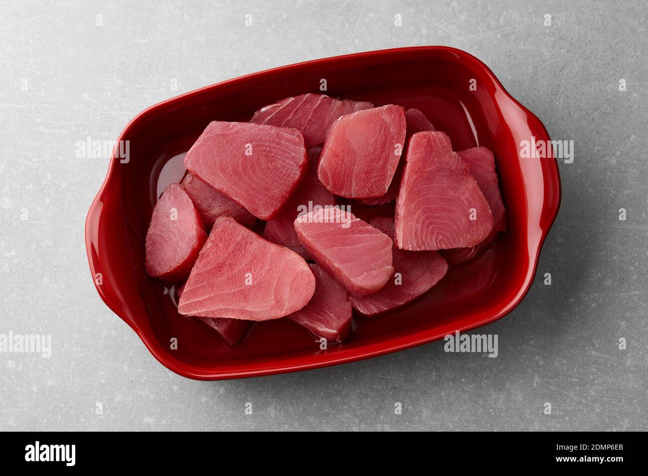Tranches de thon cru dans un plat rouge foncé sur fond gris arrière-plan en pierre Banque D'Images