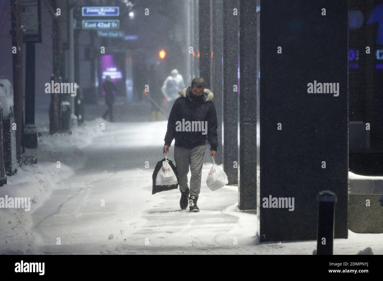Un homme transporte des articles d'épicerie dans une rue enneigée alors que la tempête de neige majeure de 2020 amène plus de 7 pouces de neige en quelques heures. Alors que le Nor’easter descend sur New York, les températures oscillent autour de 30 degrés, et des rafales de vent allant jusqu’à 30 km/h balaient la ville. Banque D'Images
