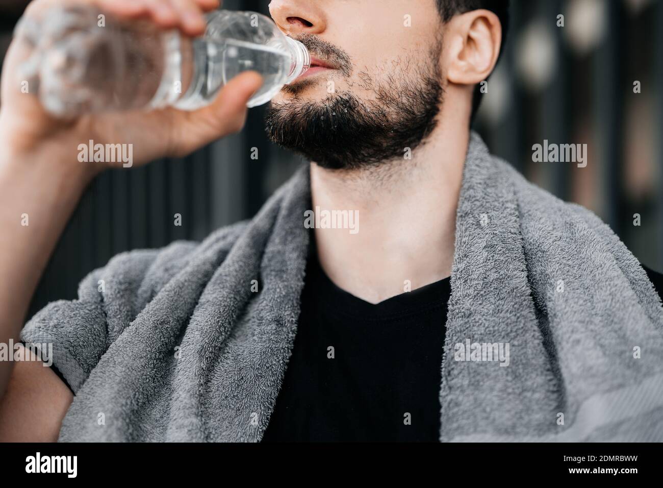 Homme buvant de l'eau de la bouteille en plastique après l'entraînement dur.  Vue en coupe rapprochée de la face mâle. N'oubliez pas de boire pendant la  formation. Prenez soin de vous-même Photo