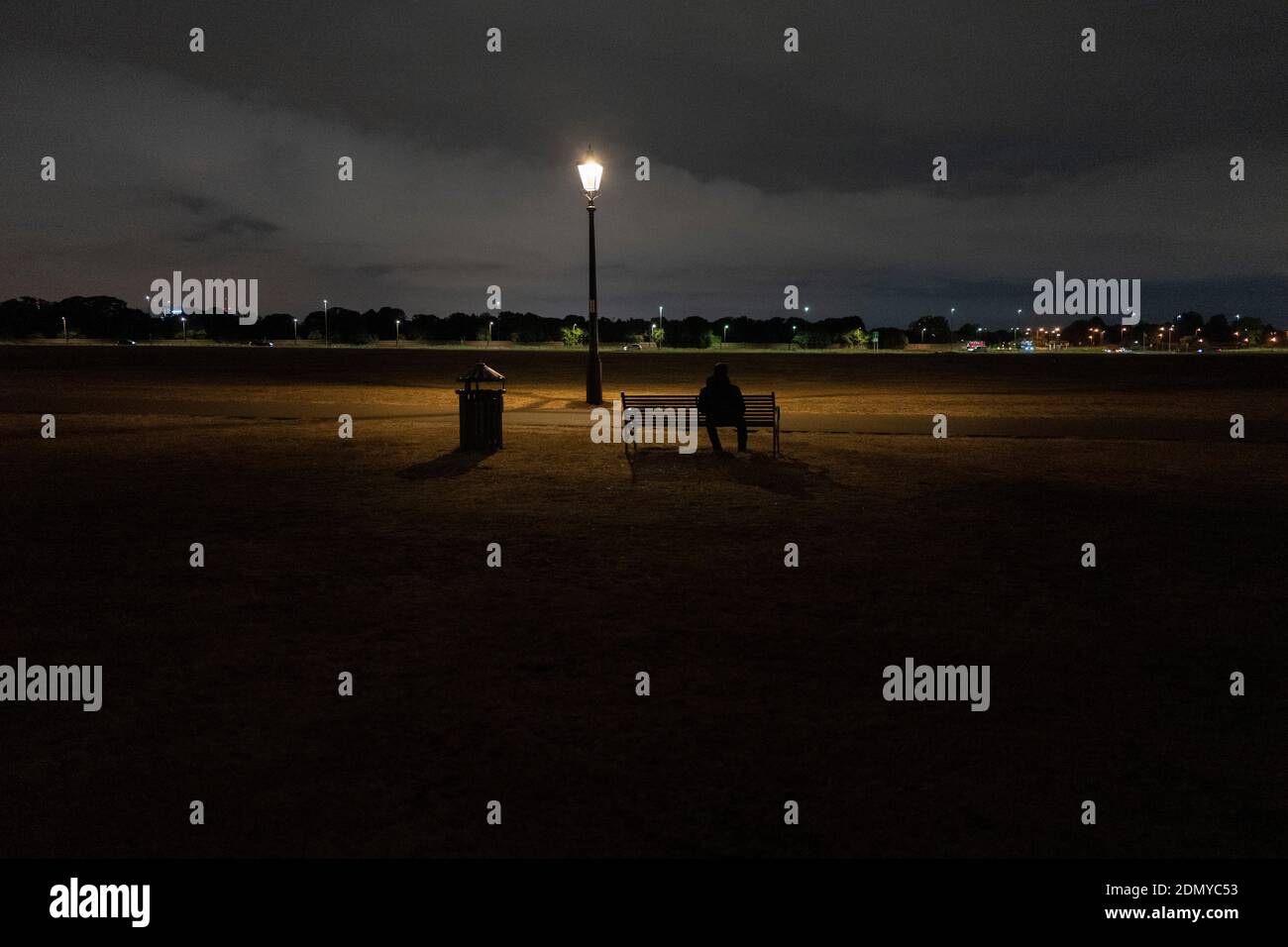 Une personne s'assoit sur un banc la nuit sur Blackheath Banque D'Images