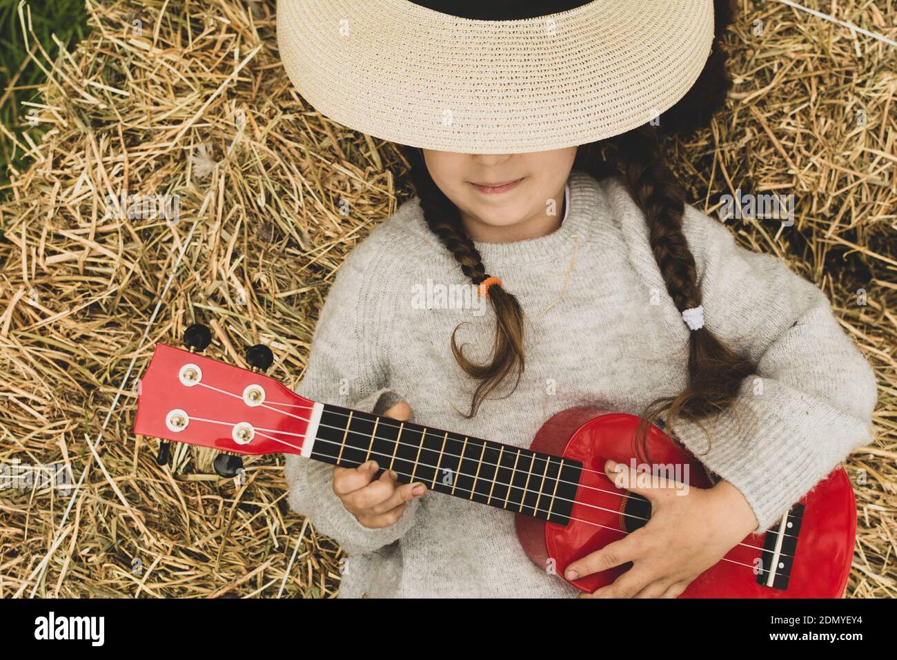 Jolie fille portant un chapeau tenant une guitare couchée sur l'herbe en  plein air Photo Stock - Alamy