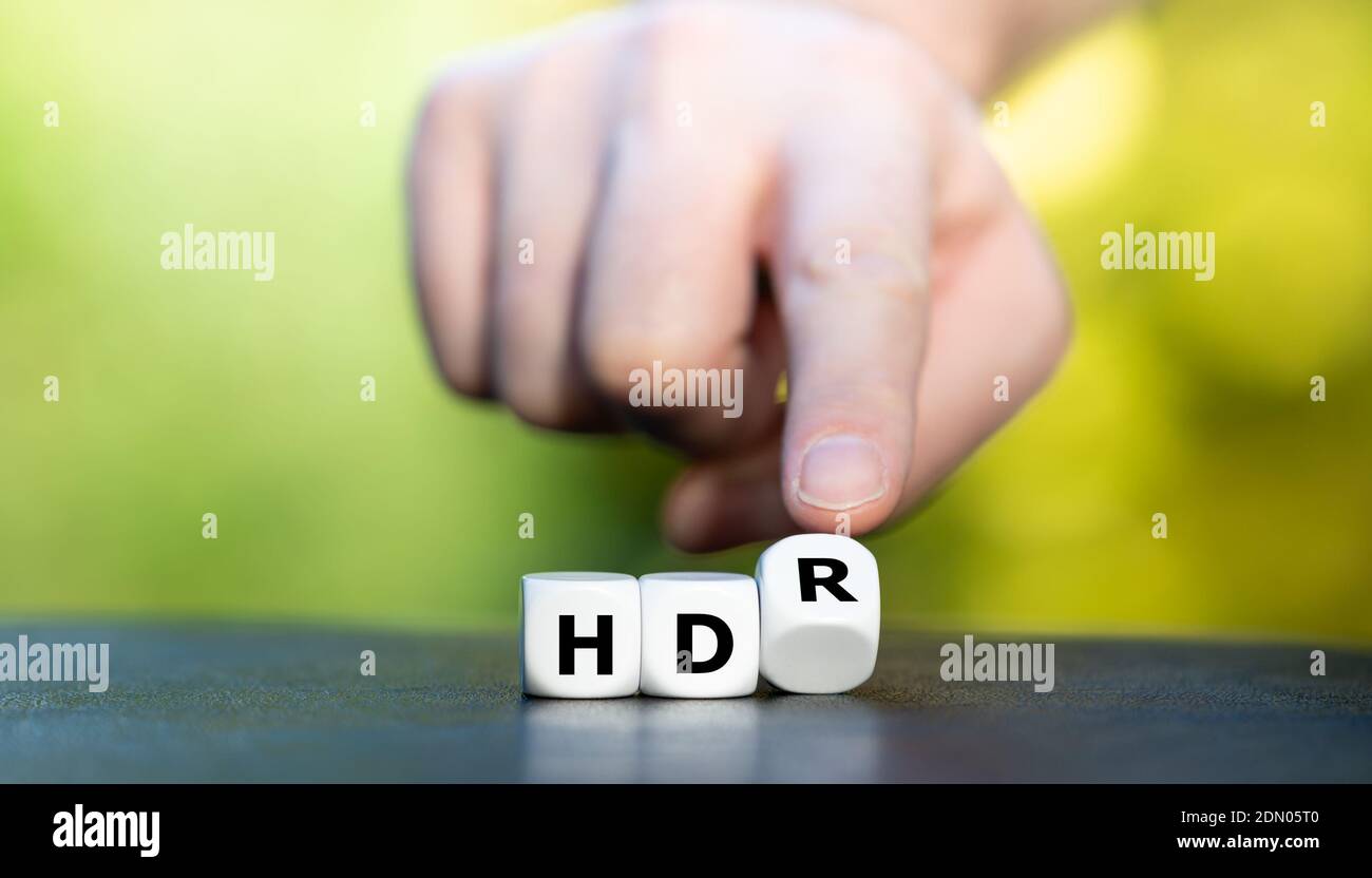 Symbole pour un téléviseur HDR (High Dynamic Range). La main tourne les dés et change l'expression « HD » en « HDR ». Banque D'Images