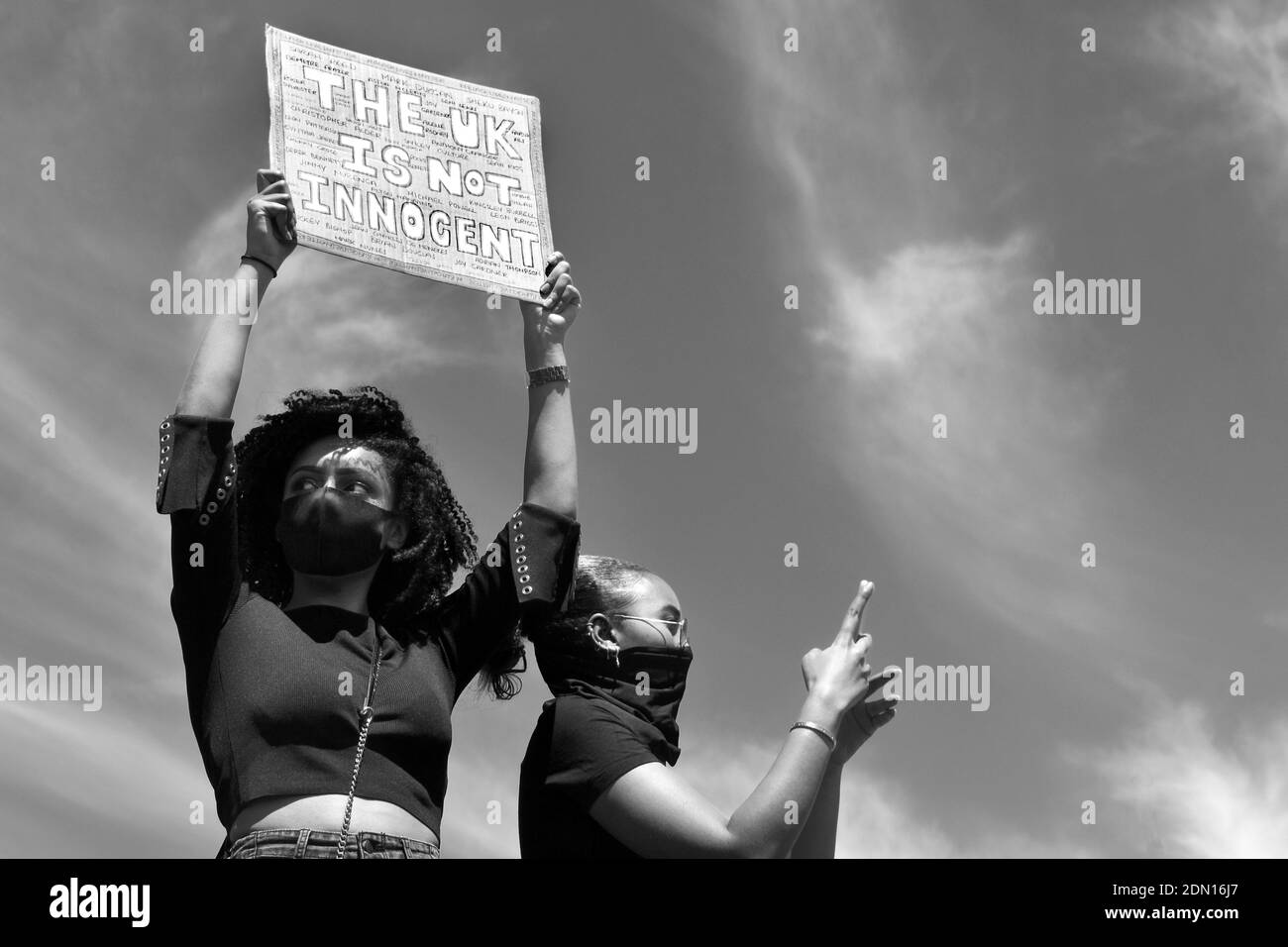 Les vies noires sont importantes en noir et blanc - une femme avec un masque tenant un écriteau sur sa tête et une autre femme prenant une photo avec son téléphone. Banque D'Images