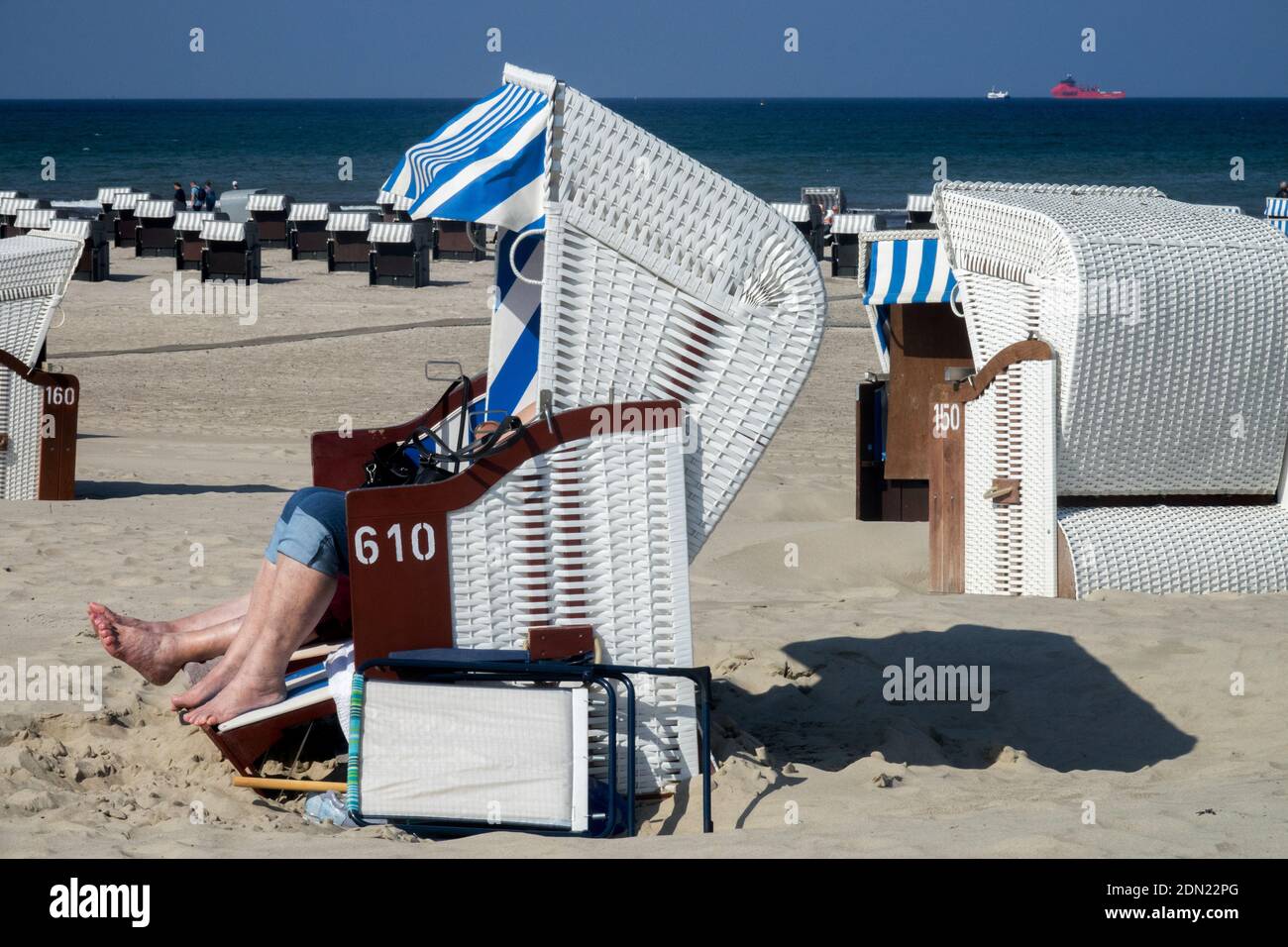 Les gens bronzer sur la plage de sable et protégé du vent dans la chaise de plage en osier Allemagne Warnemunde mer Baltique Banque D'Images