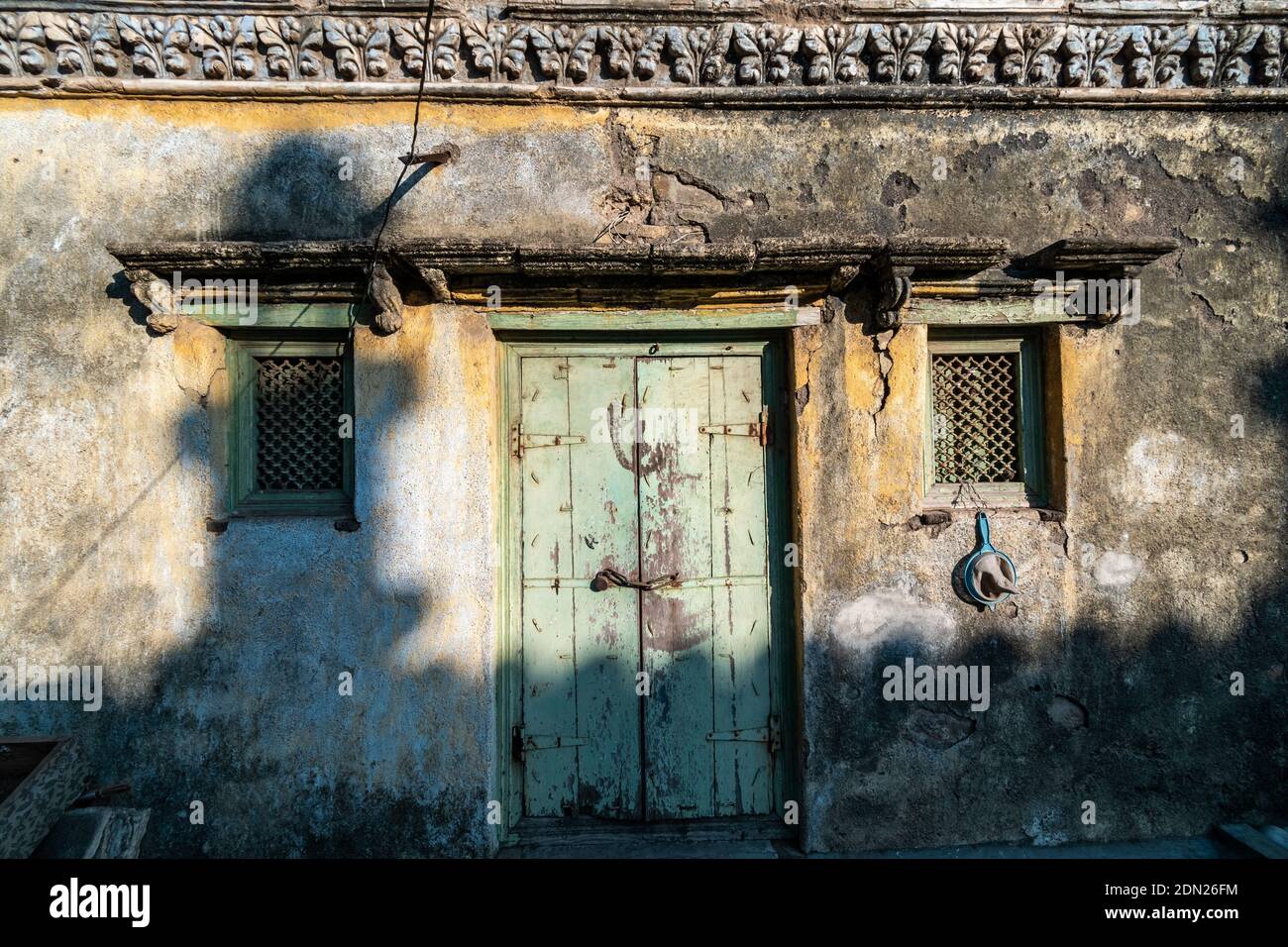 Jamnagar, Gujarat, Inde - décembre 2018 : les murs rustiques et texturés et la porte en bois d'une ancienne mosquée à l'ombre de la tour Mandvi tombant Banque D'Images