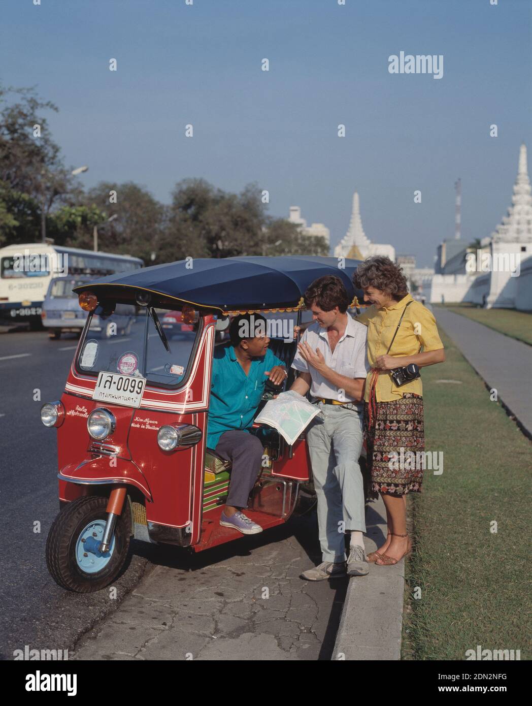 Thaïlande. Bangkok. Touristes parlant avec le chauffeur de taxi tuk-tuk au bord de la route. Banque D'Images