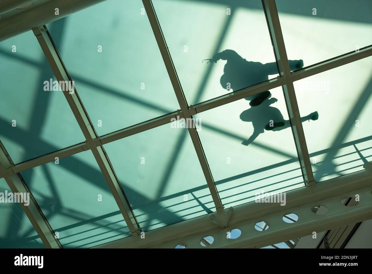 Vue de dessous à l'ombre d'un couple marchant sur un chemin à fond de verre dans le centre commercial, Lisbonne, Portugal Banque D'Images