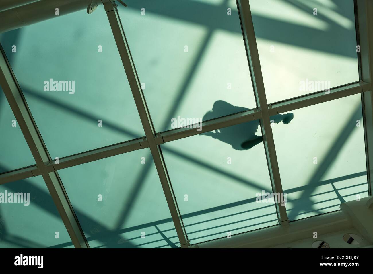 Vue de dessous à l'ombre d'une personne marchant sur un chemin à fond de verre dans le centre commercial, Lisbonne, Portugal Banque D'Images