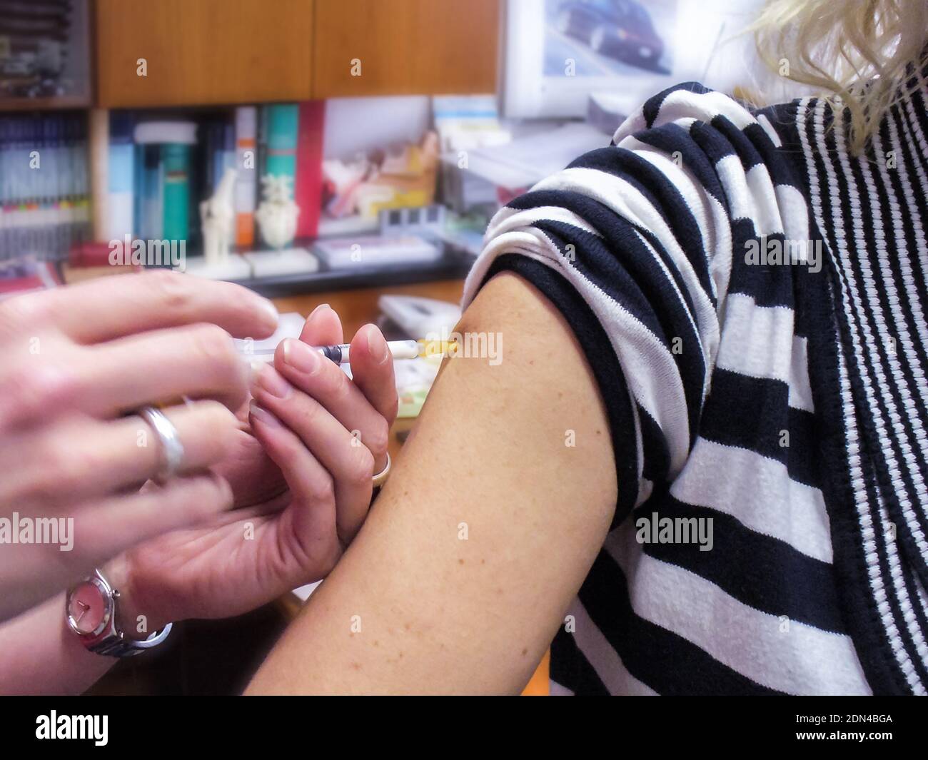 Un assistant de médecin injecte une vaccination dans le bras supérieur d'un patient. Dans un bureau de médecins. Situation réelle non posée. Banque D'Images